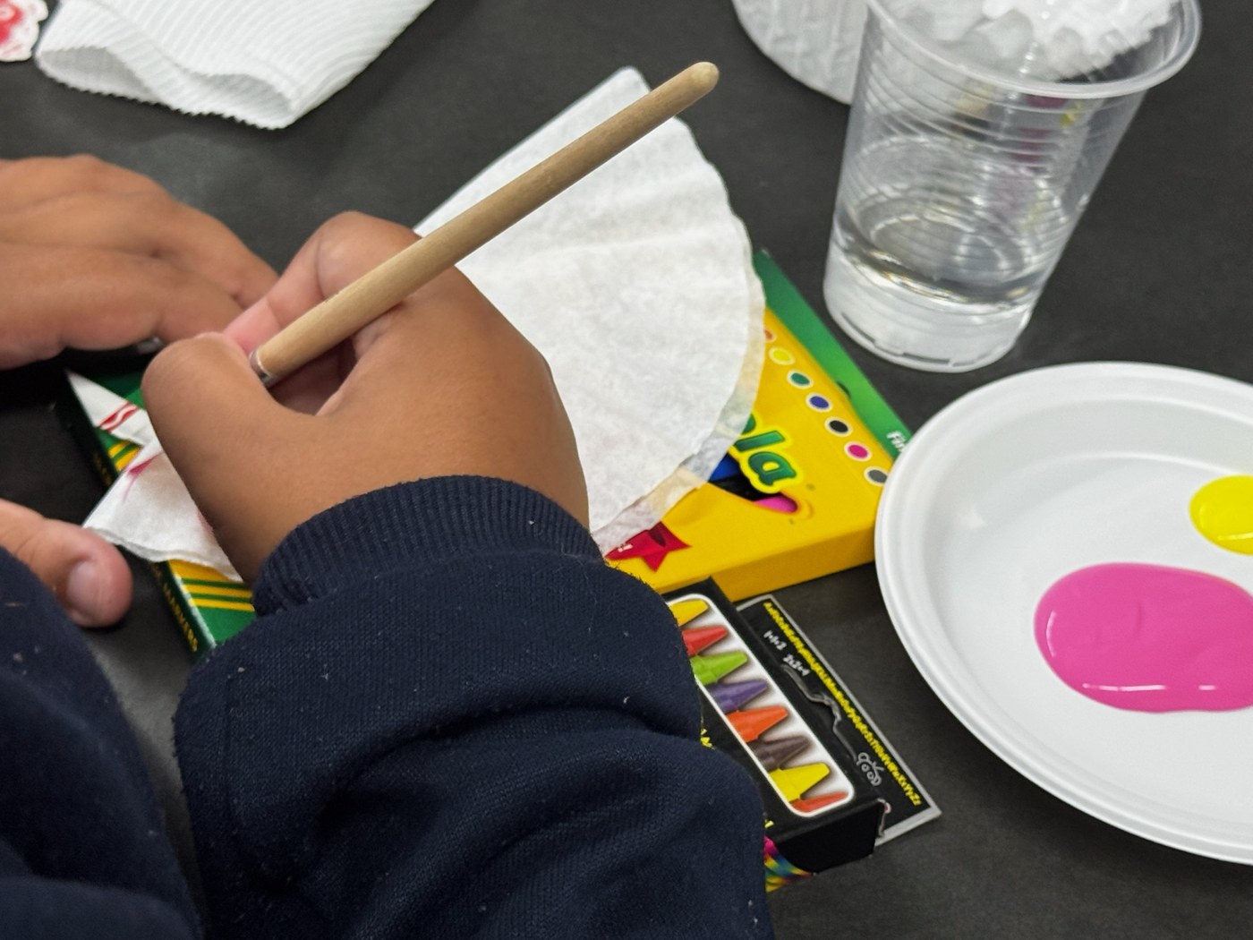 Manos de un estudiante trabajando con pintura y papel